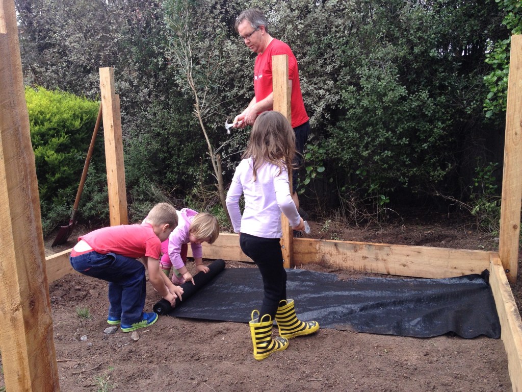 Laying down the weed mat under the sand pit